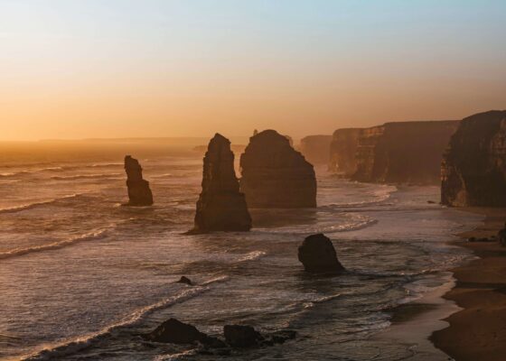 Các cột đá vôi Twelve Apostles trên Great Ocean Road dưới ánh hoàng hôn vàng rực bên bờ biển nước Úc.