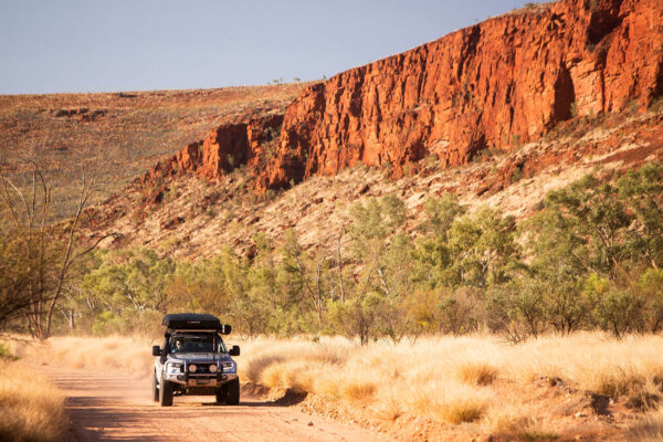 Xe 4WD chạy trên đường đất đỏ giữa vách đá West MacDonnell Ranges, Úc
