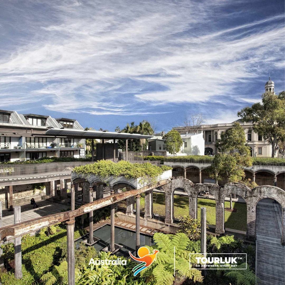 View of Paddington Reservoir Gardens in Sydney, Australia, featuring historic sandstone structures, landscaped gardens, and a dramatic blue sky with clouds.