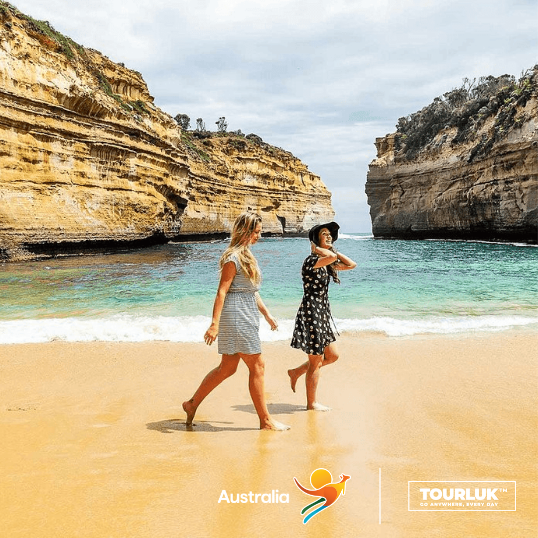 Du khách dạo bộ trên bãi cát vàng tại Loch Ard Gorge, nổi bật với làn nước xanh ngọc và những vách đá vôi hùng vĩ thuộc Great Ocean Road, Victoria.