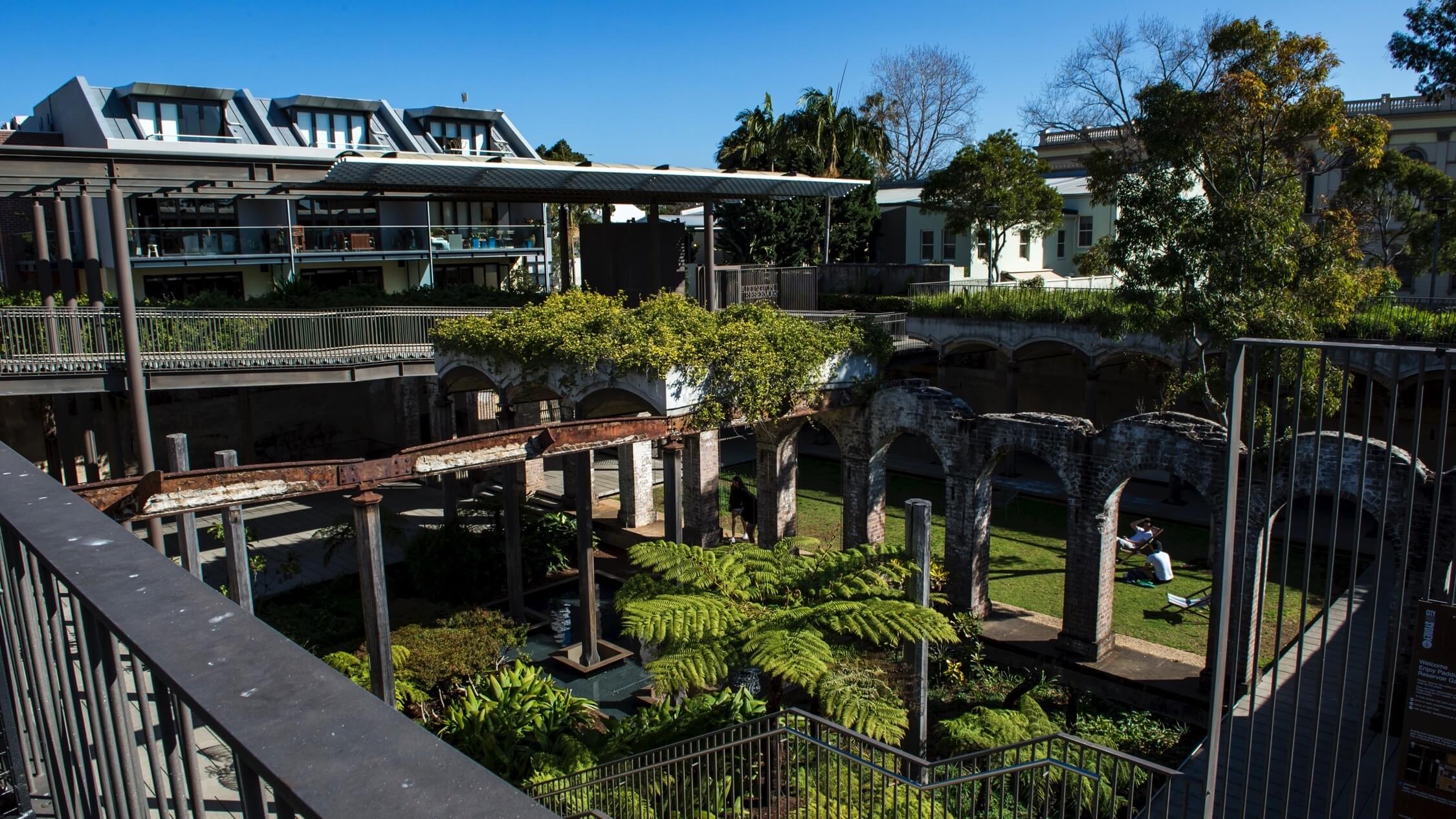 Historic sandstone ruins and gardens at Paddington Reservoir Gardens in Sydney, Australia, surrounded by modern urban buildings and greenery.