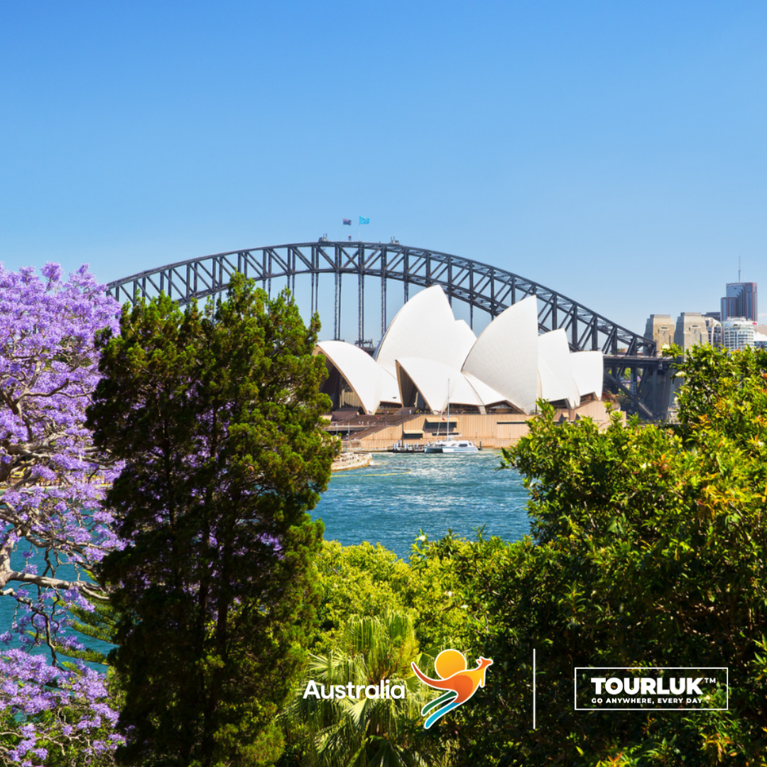 Khung cảnh Nhà hát Opera Sydney và Cầu Cảng Sydney nổi bật giữa không gian xanh mát, nhìn từ khu vườn ven cảng vào một ngày nắng đẹp.